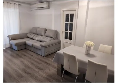Sofá chaislongue Ares con asientos deslizantes, brazos con arcón y tapizado personalizable en un salón moderno.