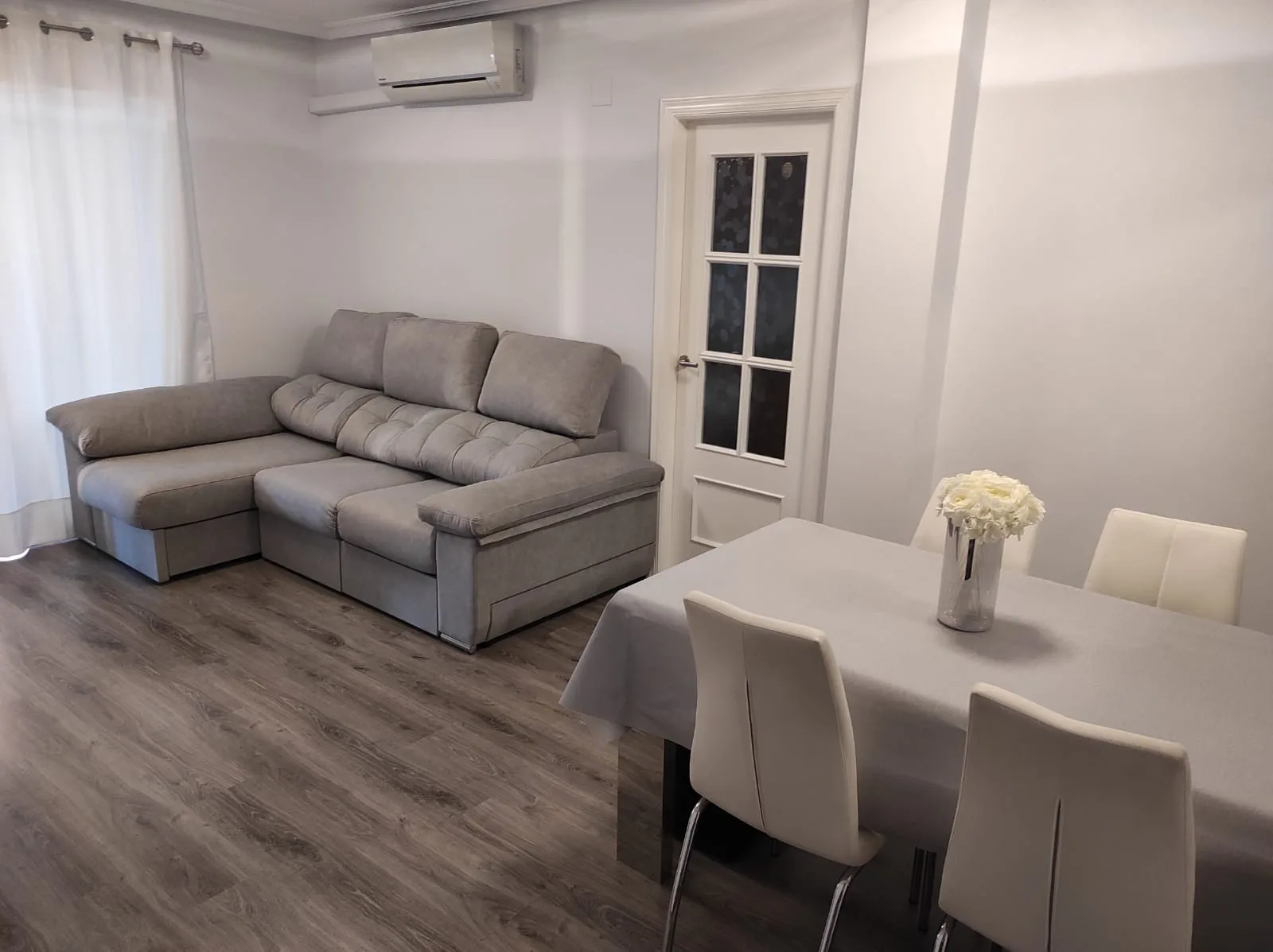 Sofá chaislongue Ares con asientos deslizantes, brazos con arcón y tapizado personalizable en un salón moderno.